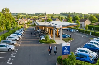 Parking de covoiturage avec station VINCI, voitures et village rural.
