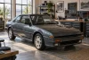 Une voiture générique inspirée des années 1980-1990 est entretenue dans un garage lumineux.