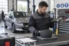 Un technicien contrôle sur tablette un module d’airbag intact et fermé dans un atelier professionnel.