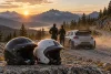 Deux silhouettes non identifiables vues de dos se tiennent près d’une voiture de rallye générique et de deux casques.